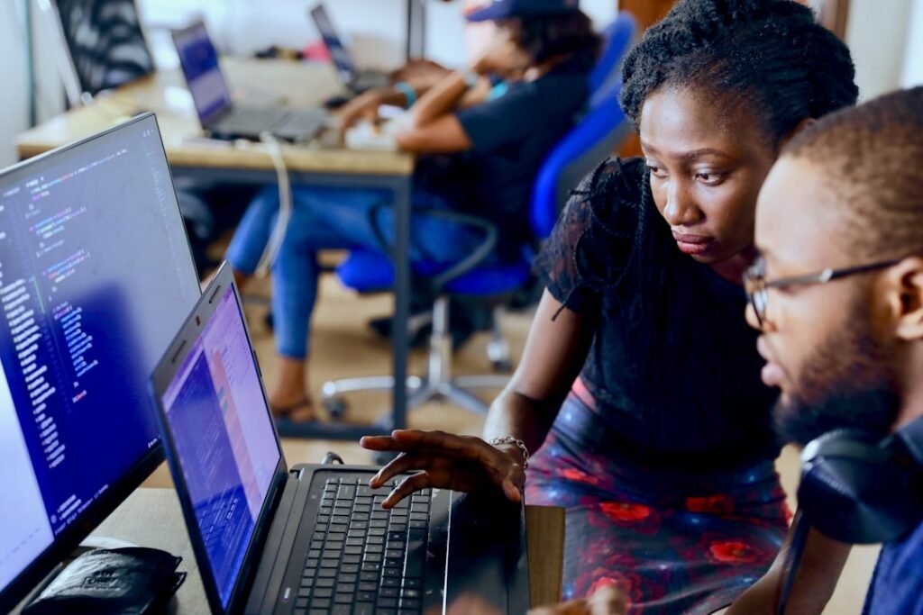 Developers working side by side on laptops building a data pipeline