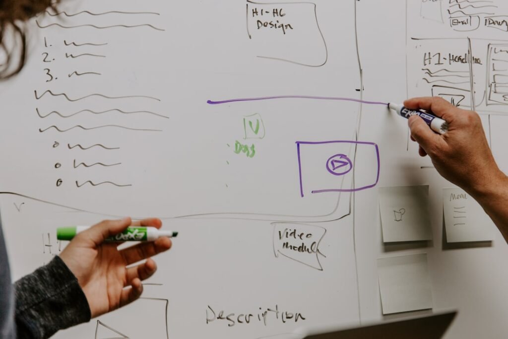 Two colleagues mapping a data flow diagram on a whiteboard