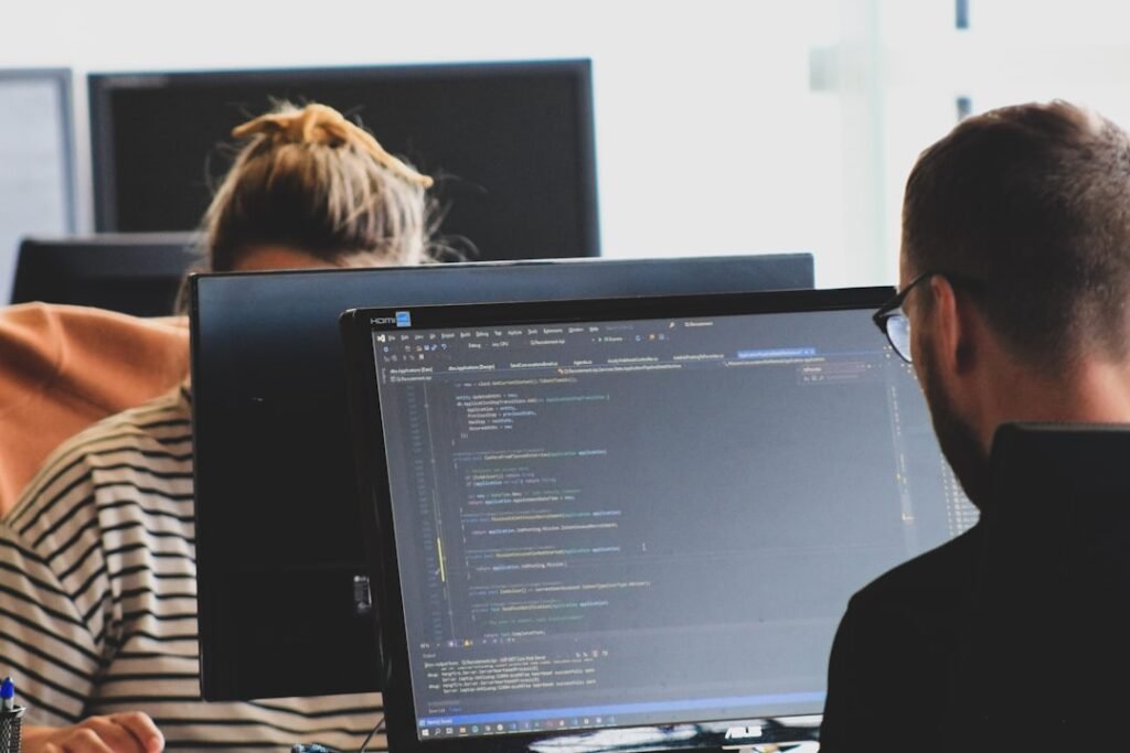 Two engineers reviewing code together at dual monitors