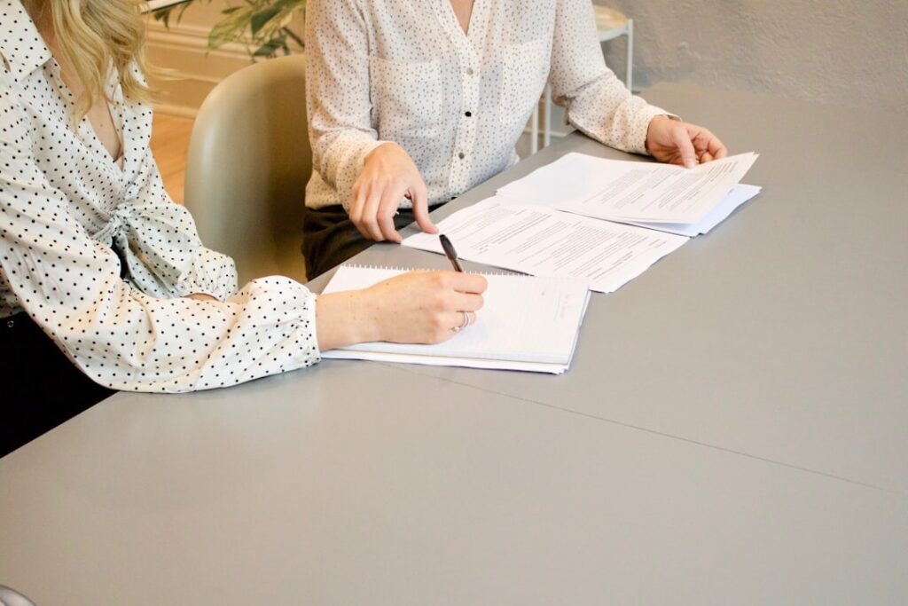 Two people reviewing and signing contract documents at a desk